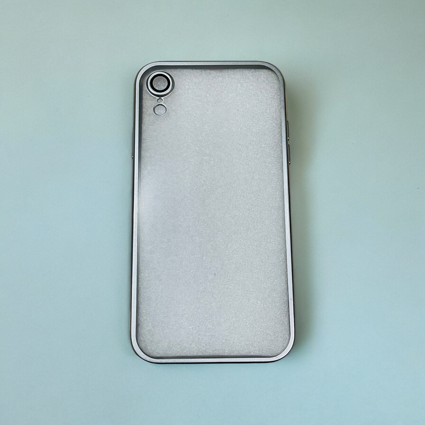 The Zivikart Elegant Electroplated Case for Apple iPhone features a sleek silver back cover with a single rear camera positioned in the top left corner, enhanced with durable materials for added protection. The phone is displayed on a light, soft-gradient background transitioning from blue to green.