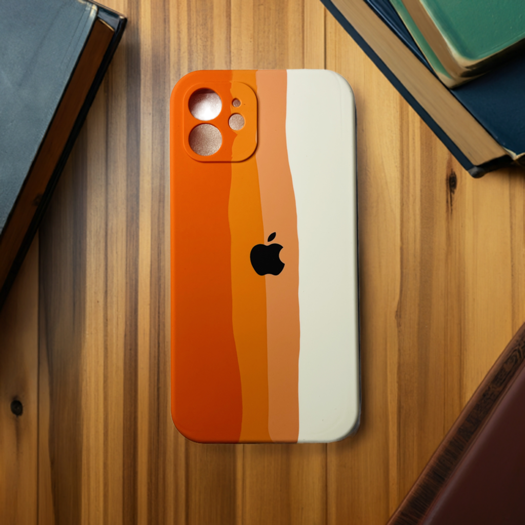 A smartphone lies on a wooden table surrounded by books, encased in a striped, multicolored cover in shades of orange and cream. The ZIVIKART Silicone Case for iPhone 12 Series features peel-off layers revealing different hues, an Apple logo at the center, and a soft microfiber lining to ensure protection for your device.