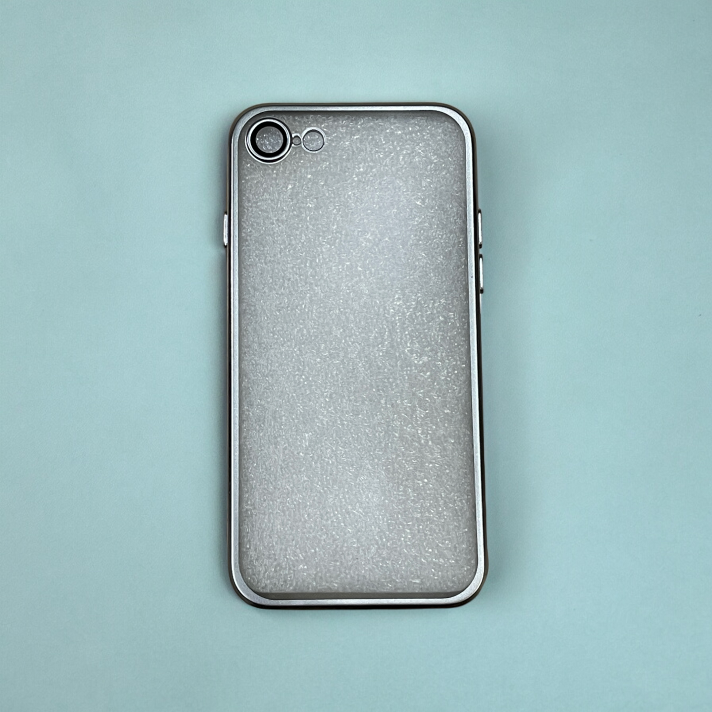 The ZIVIKART Elegant Electroplated Case with Camera Protection for Apple iPhone, featuring a partially frosted, semi-transparent design, rests on a light blue surface. The phone's rear camera lens and flash are visible in the top left corner of the device. Made by Zivikart, the durable material gives it a smooth texture with a slightly glittery appearance.